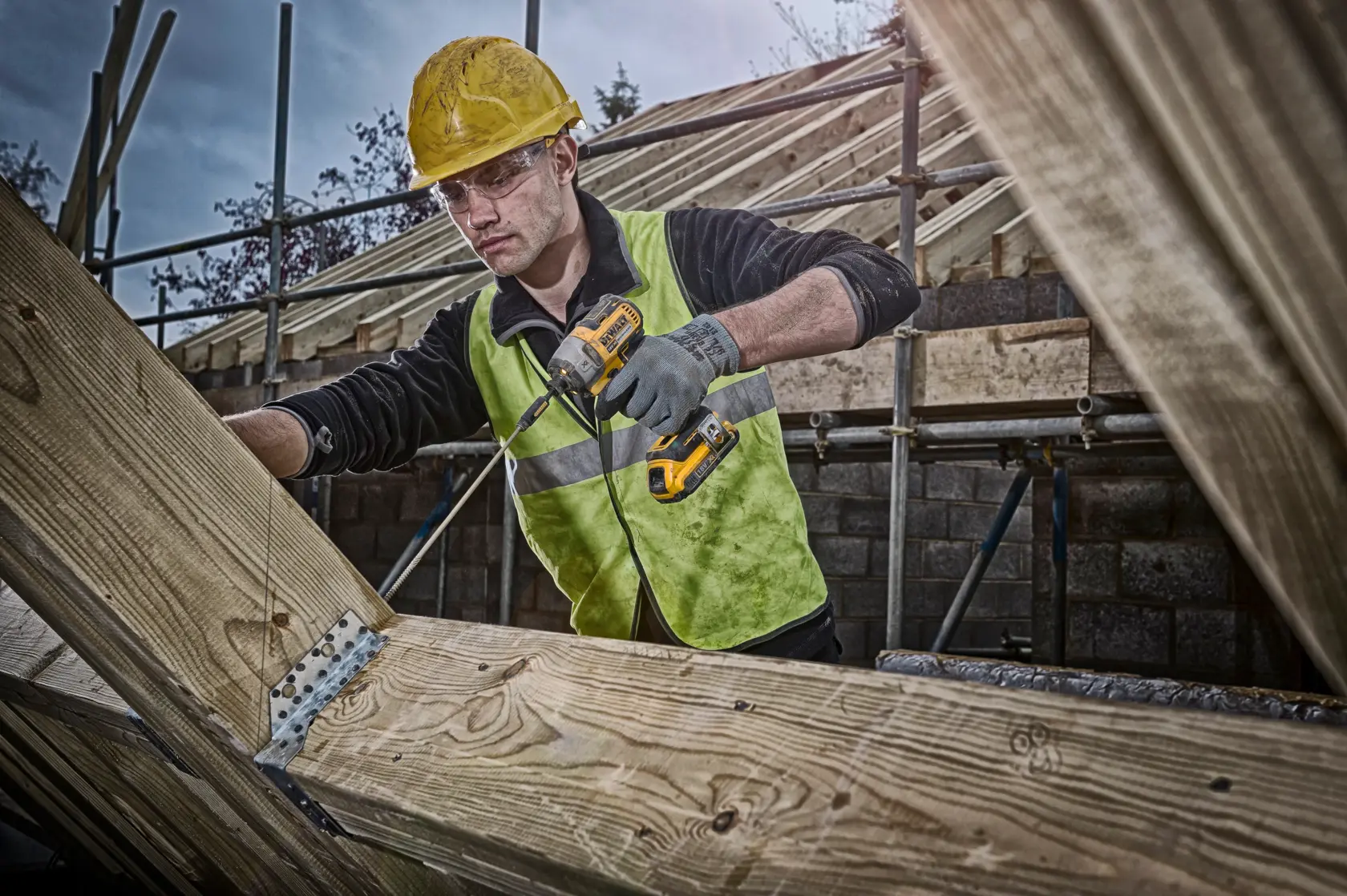DEWALT DCF887NT, DCF887NT-XJ, DCF887N-XJ impact driver in use on wood by worker wearing helmet and vest at construction site.